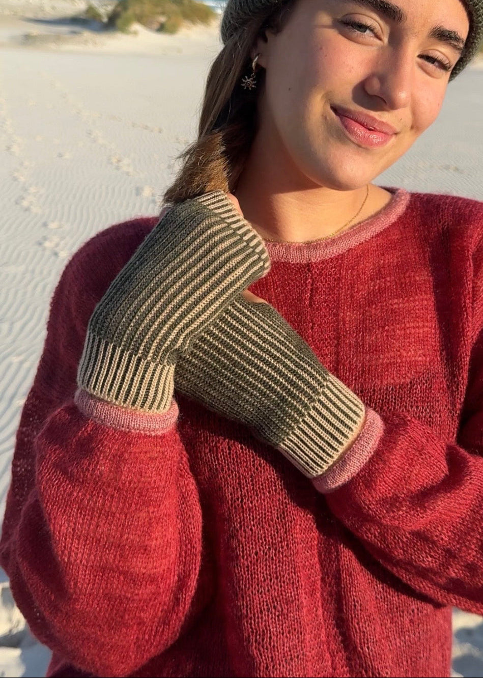 girl with beanie and brioche knit fingerless gloves standing on a beach