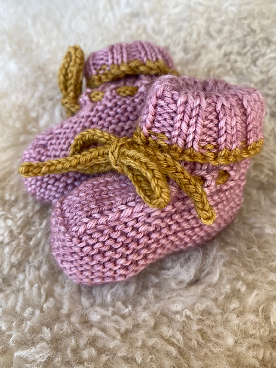 Hand-knitted pink baby booties in merino wool