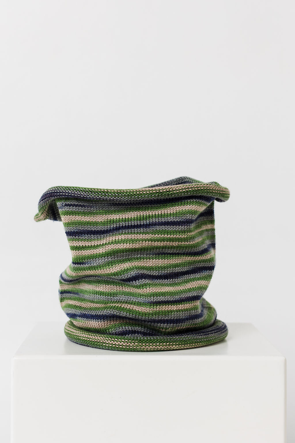 Knitted wool neck warmer with green and blue pattern on a white background