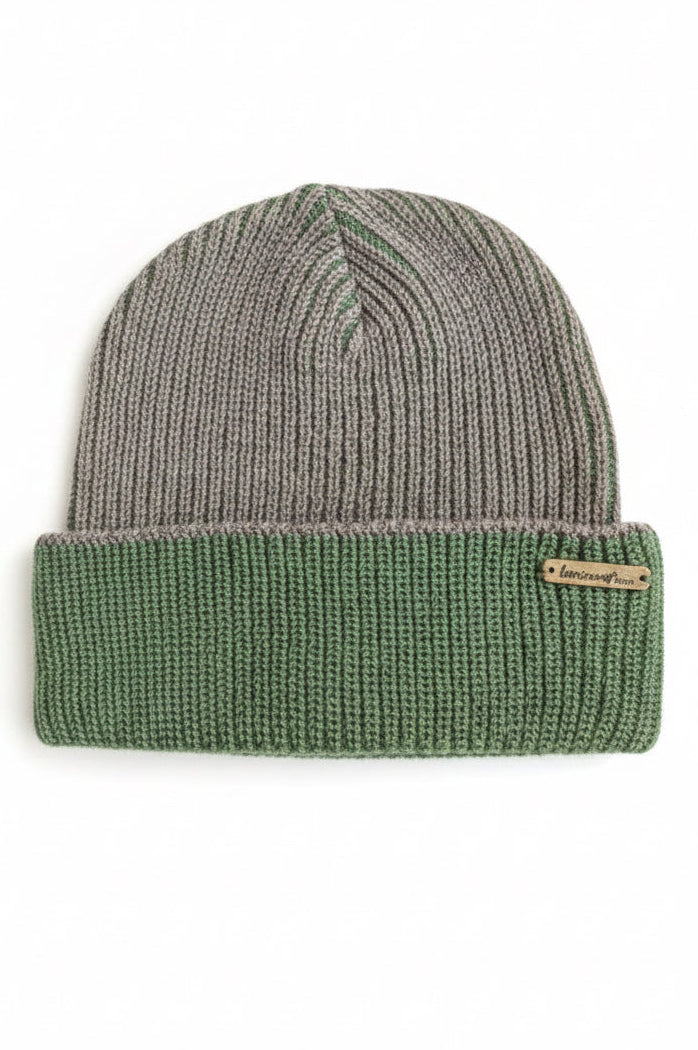 A ribbed knit beanie hat in a mushroom and green colorway, featuring a solid green folded cuff with a small metal brand tag that reads 'Luminous Ware'. 