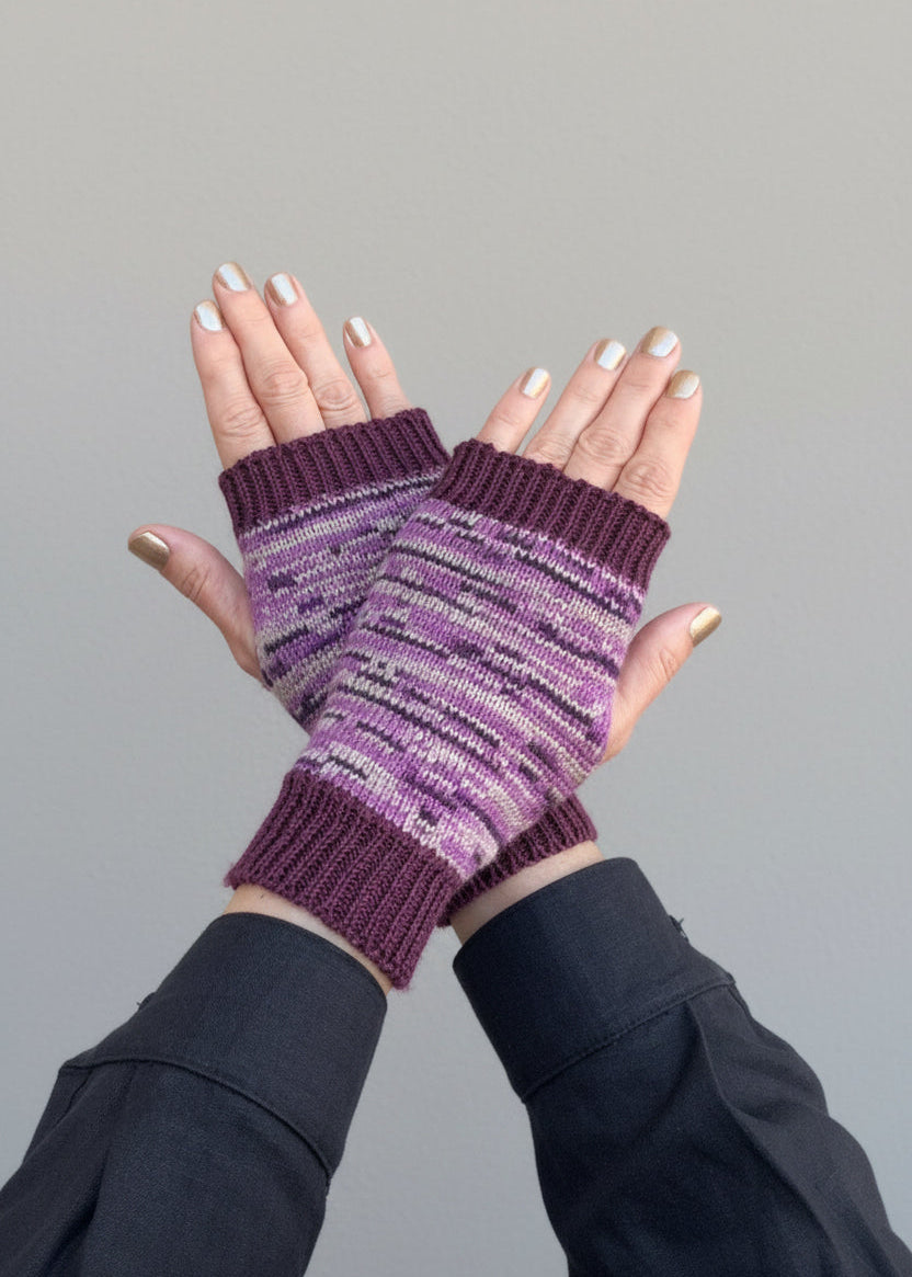 Purple striped wool gloves worn by a person against a gray background